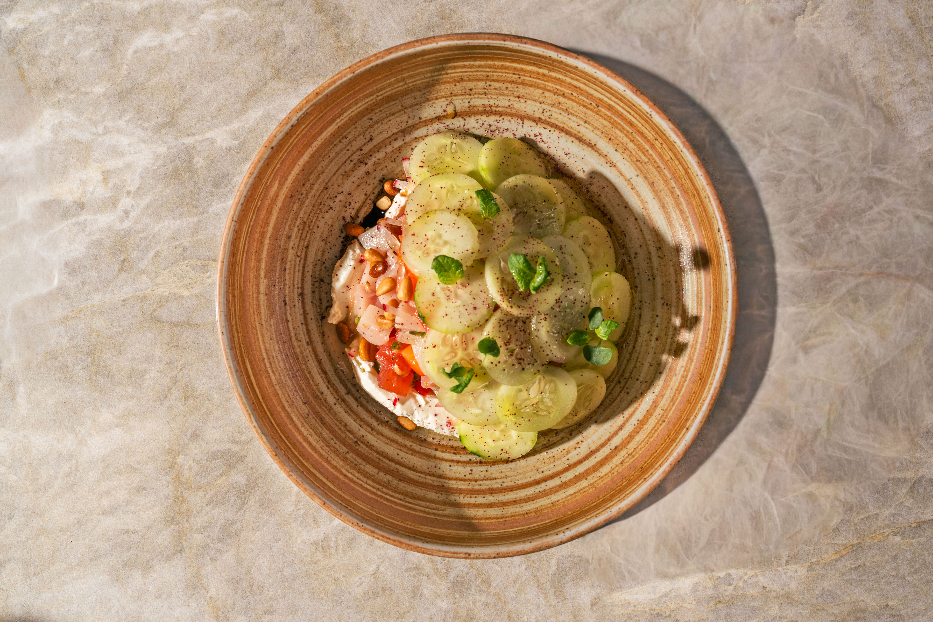 Seasonal cucumber ceviche with fresh herbs on a ceramic plate at Petra